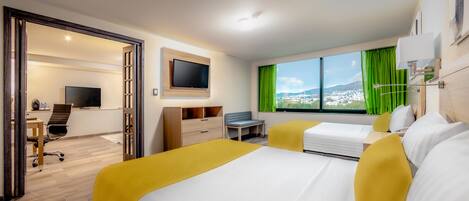 A hotel room with a bed, a desk, a chair, a TV, and a window with a view of a cityscape.