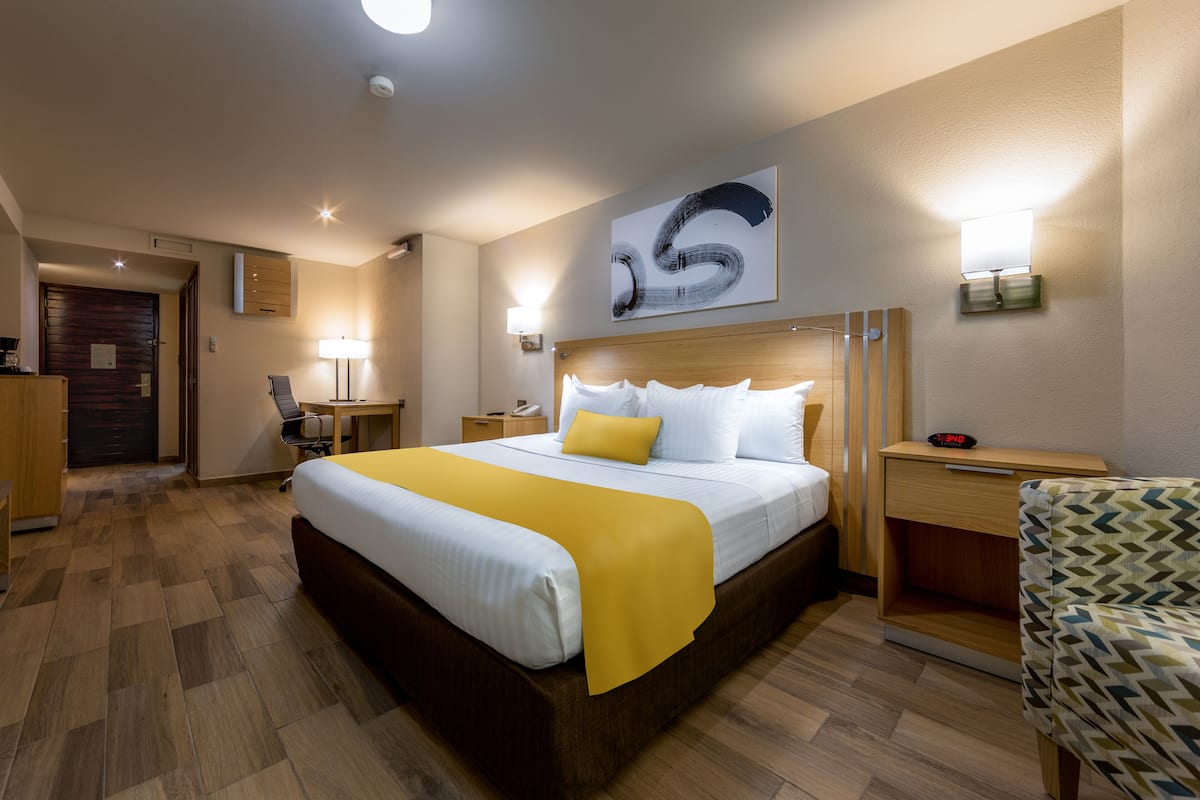 Une chambre d’hôtel avec un grand lit, des tables de chevet, un bureau et une chaise.