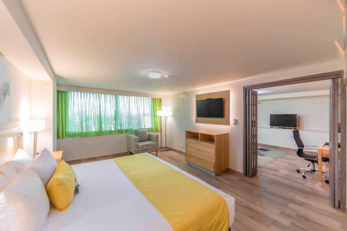 Une chambre d’hôtel avec un lit, un bureau, une chaise et un téléviseur.