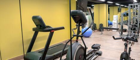 A gym with treadmills, elliptical machines, and free weights.