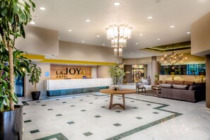 A hotel lobby with a reception desk, a seating area, and a chandelier.