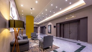 A modern lobby with a marble floor, a sofa, armchairs, a floor lamp, and a painting. - La Joya Pachuca (Pachuca)