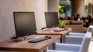 Two HP desktop computers on wooden desks in a modern office setting with grey chairs and a plant in the background. - La Joya Pachuca (Pachuca)