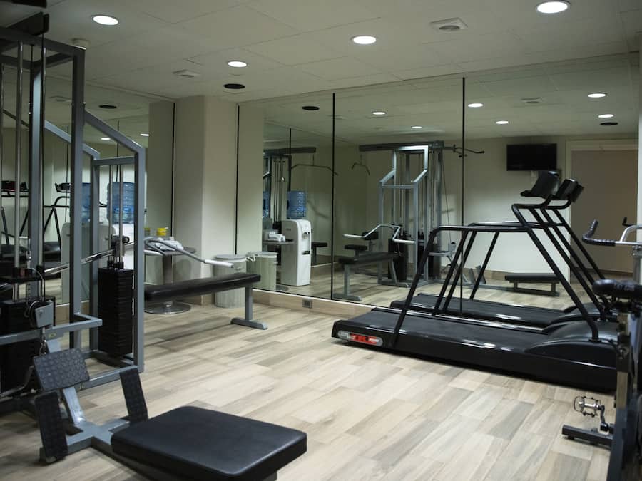 Un gimnasio con equipo de ejercicio, incluyendo una cinta de correr, máquinas de pesas y un banco.