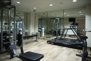 A gym with exercise equipment including a treadmill, weight machines, and a bench.