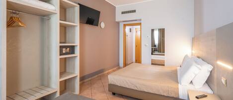 A bedroom with a bed, a bedside table, a TV mounted on the wall, a wardrobe, and a door leading to another room.