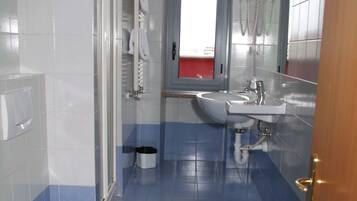 Une salle de bain avec deux toilettes, un lavabo et une douche.