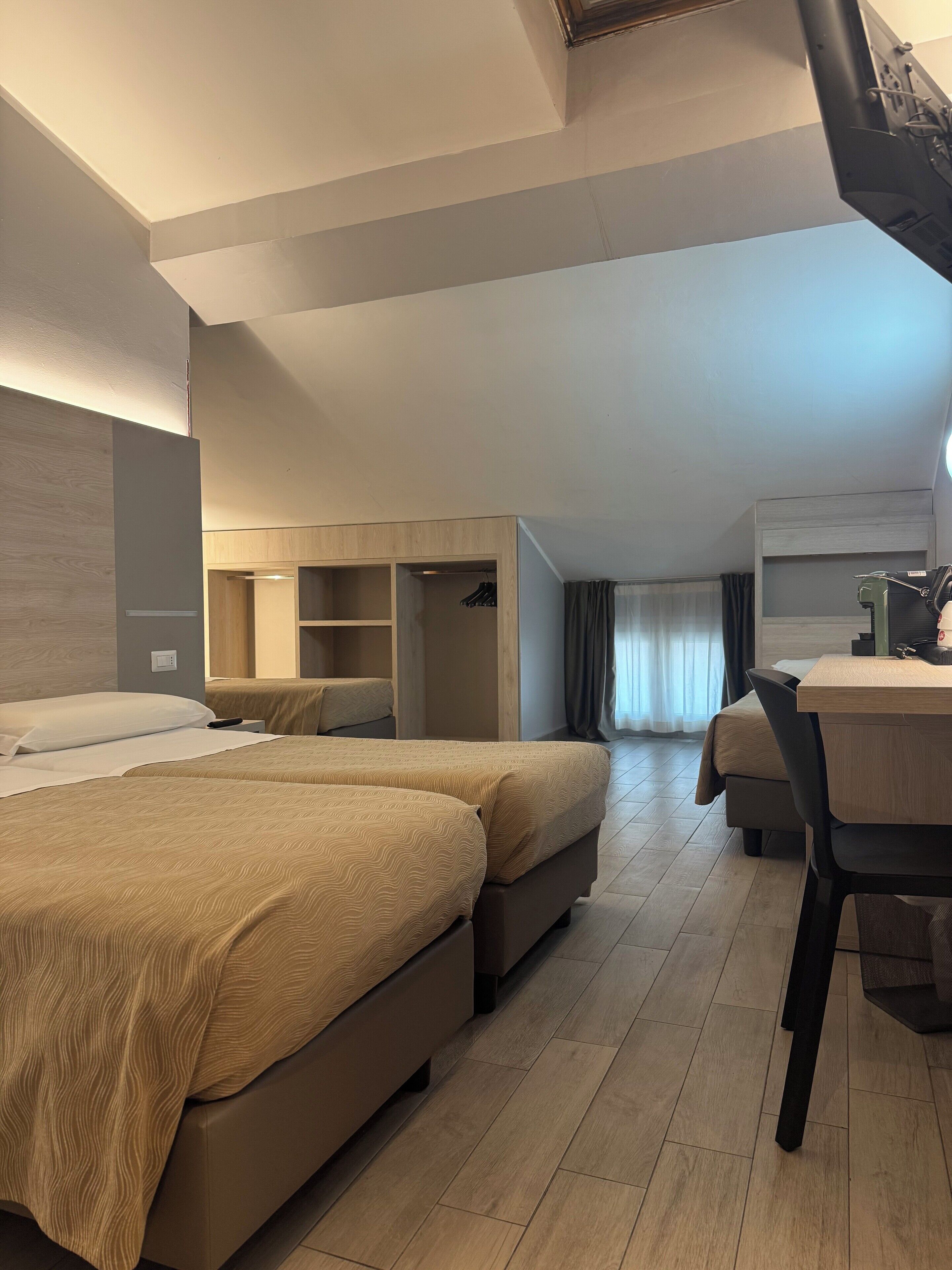 A hotel room with two beds, a desk, and a wardrobe.