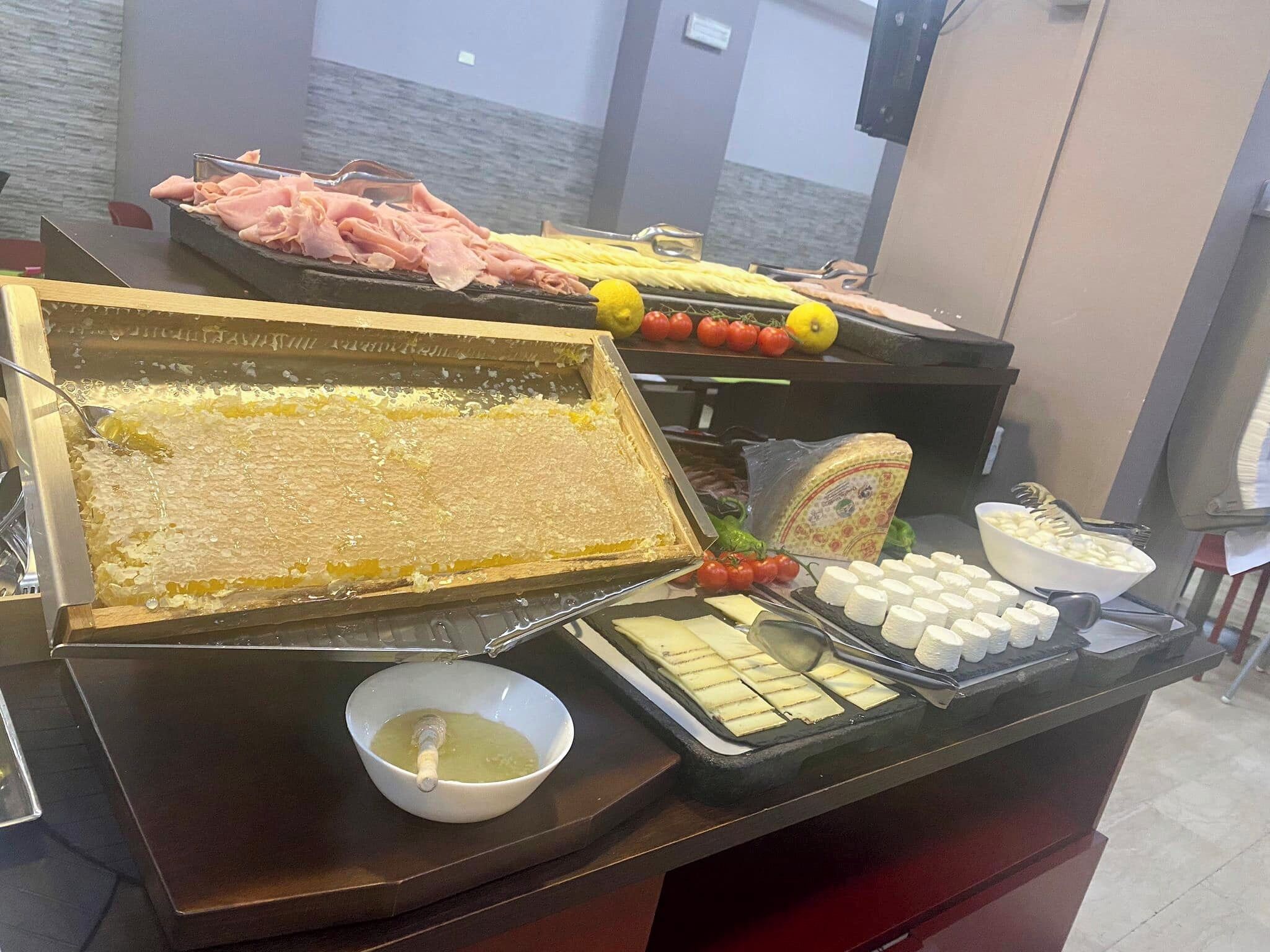 Een buffet met diverse soorten eten, waaronder kaas, tomaten en een bakje dipsaus.
