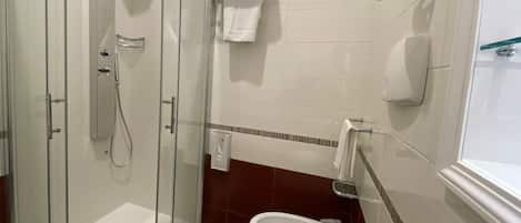 A bathroom with a glass-enclosed shower, a sink, and a toilet.