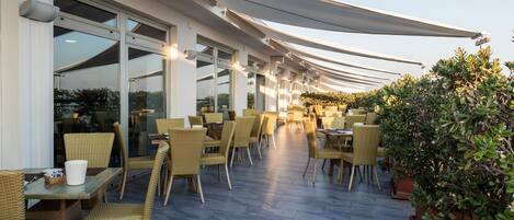 An outdoor café with wicker furniture and large windows.