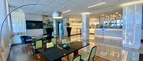 A modern conference room with a large table, green chairs, and a TV screen.
