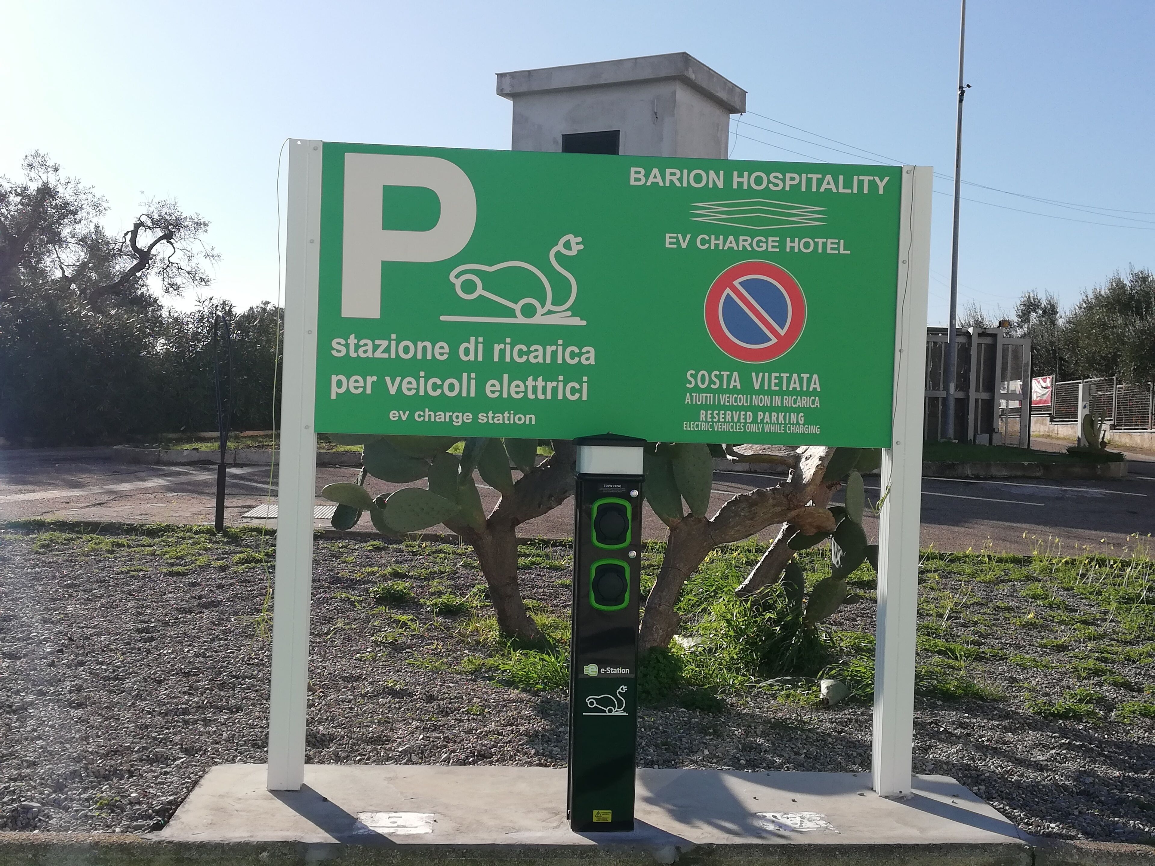 A parking sign for an EV charge station at BARION HOSPITALITY, indicating reserved parking for electric vehicles only while charging.