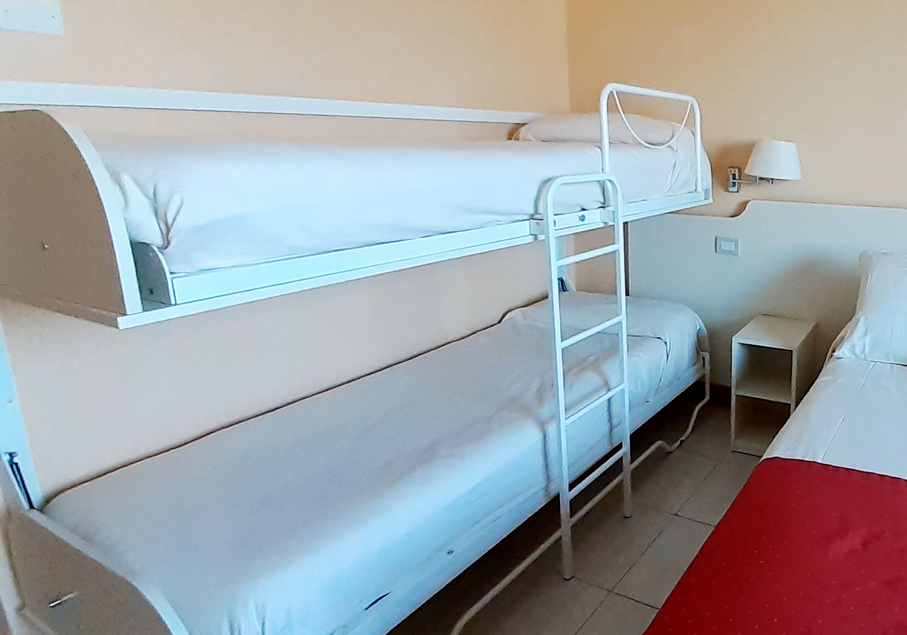 A bunk bed room with a small bedside table and a lamp.
