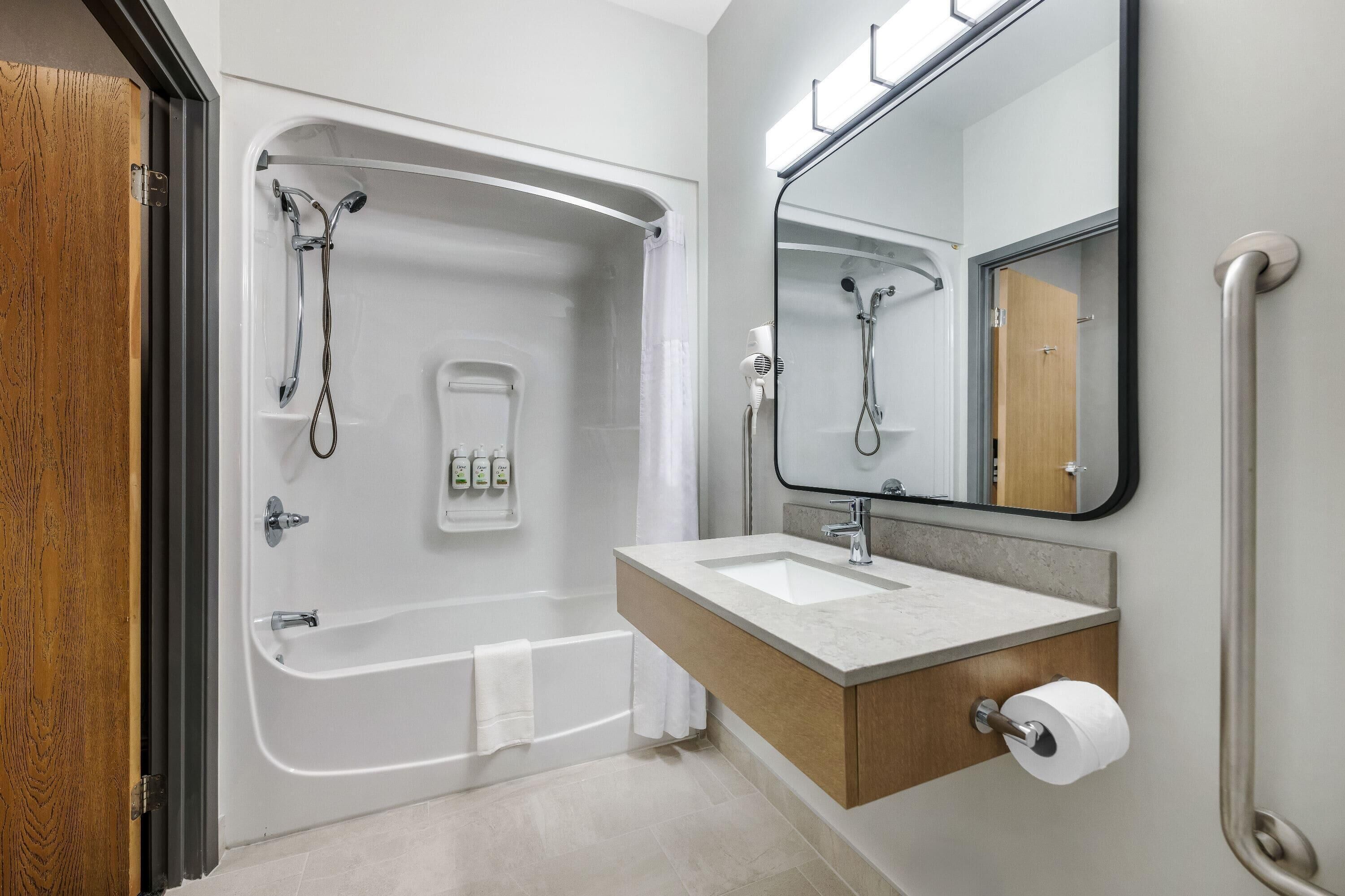 A modern bathroom with a bathtub, a sink, a mirror, and a shower.