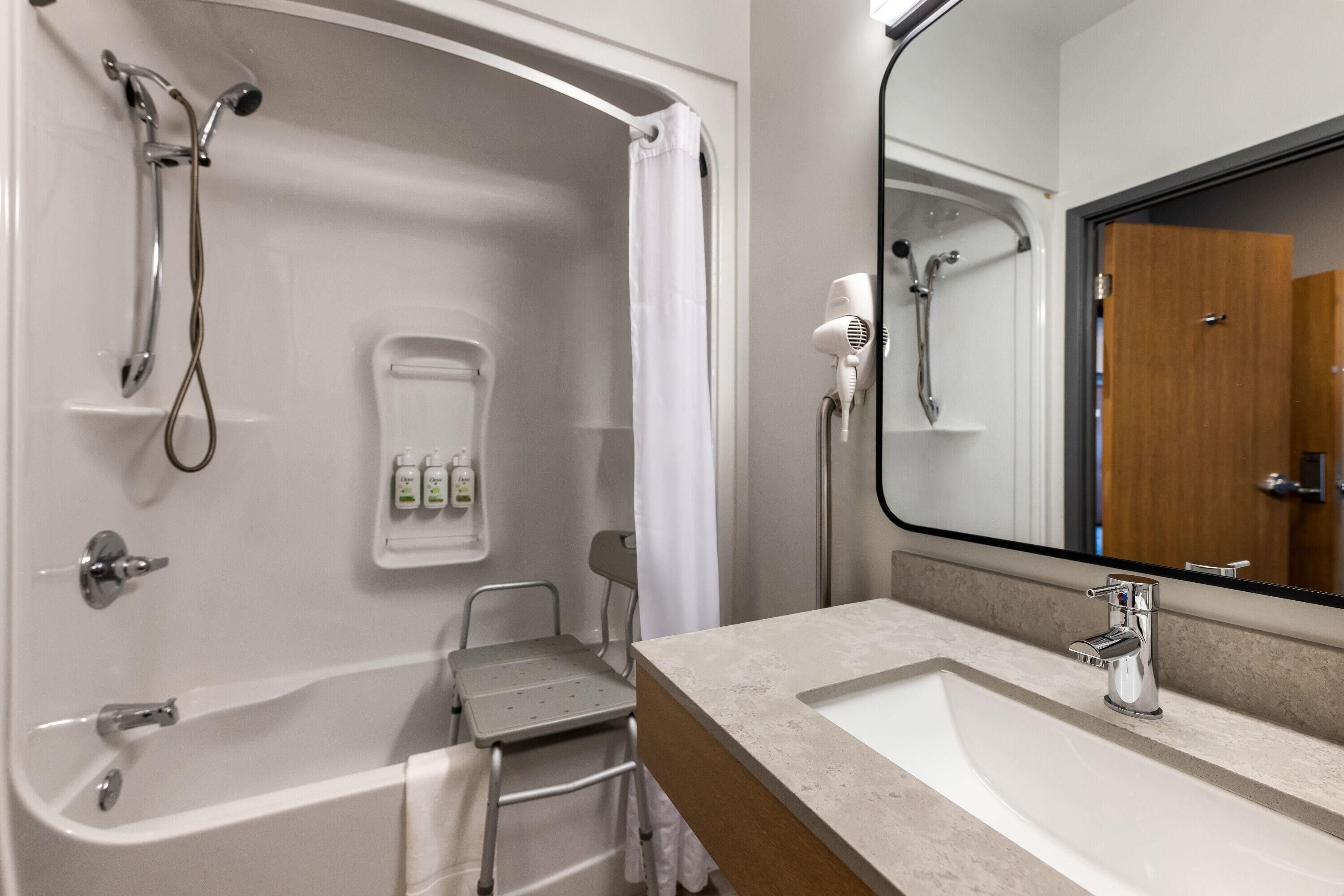 A bathroom with a bathtub, shower, and a vanity with a mirror.