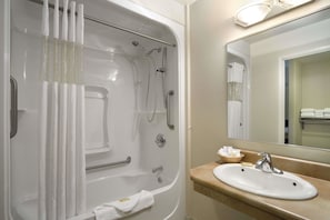 Une salle de bain avec une baignoire, un lavabo et un miroir.