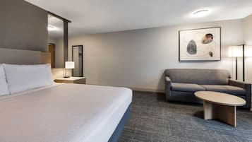 Une chambre d’hôtel avec un grand lit, un canapé, une petite table, une lampe et un tableau au mur.