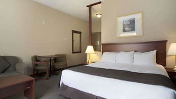 A hotel room with a large bed, a desk, a chair, and a small table.