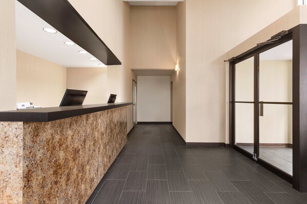 A reception area with a marble counter, a black ceiling, and a glass door leading to a balcony.