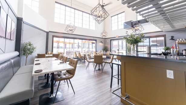 A spacious dining area with high ceilings, large windows, and modern pendant lighting.