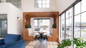 A modern interior with a blue sofa, wooden accents, and large windows offering a view of the parking lot.