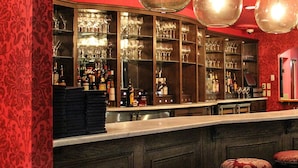 A bar with a curved counter, shelves with bottles, and stools.