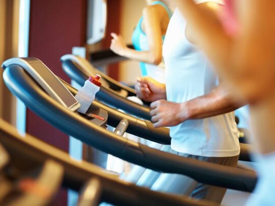 A treadmill in a gym with a visible control panel and a person using it.
