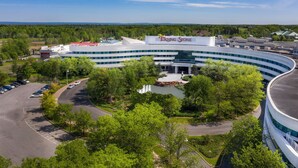 A modern building with a curved facade, a large sign reading 'Turning Stone,' and a parking lot with trees in the foreground.