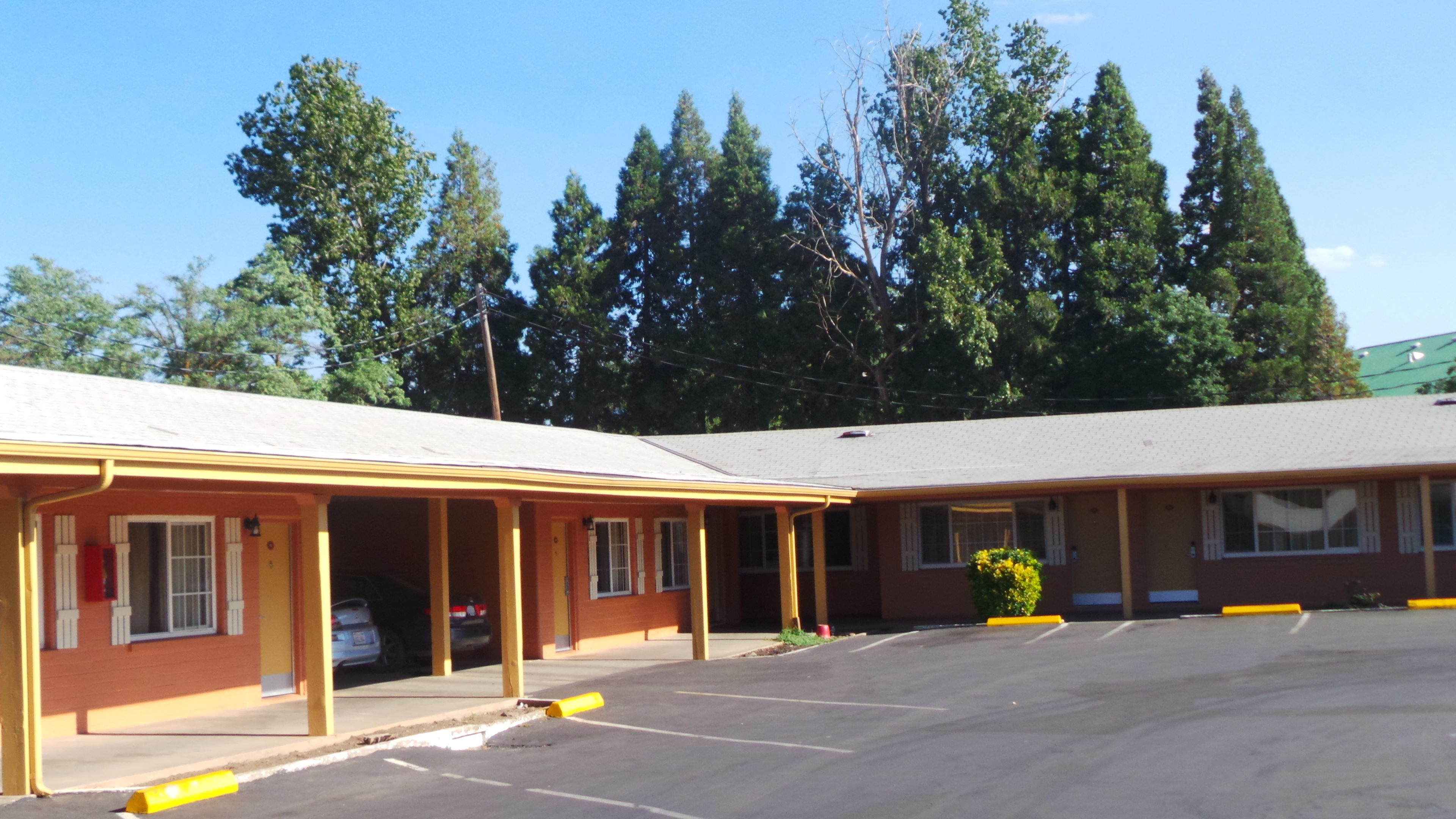 A motel with a covered parking area and a row of rooms.