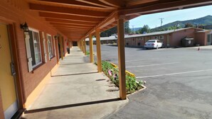Um motel com galeria coberta e estacionamento.