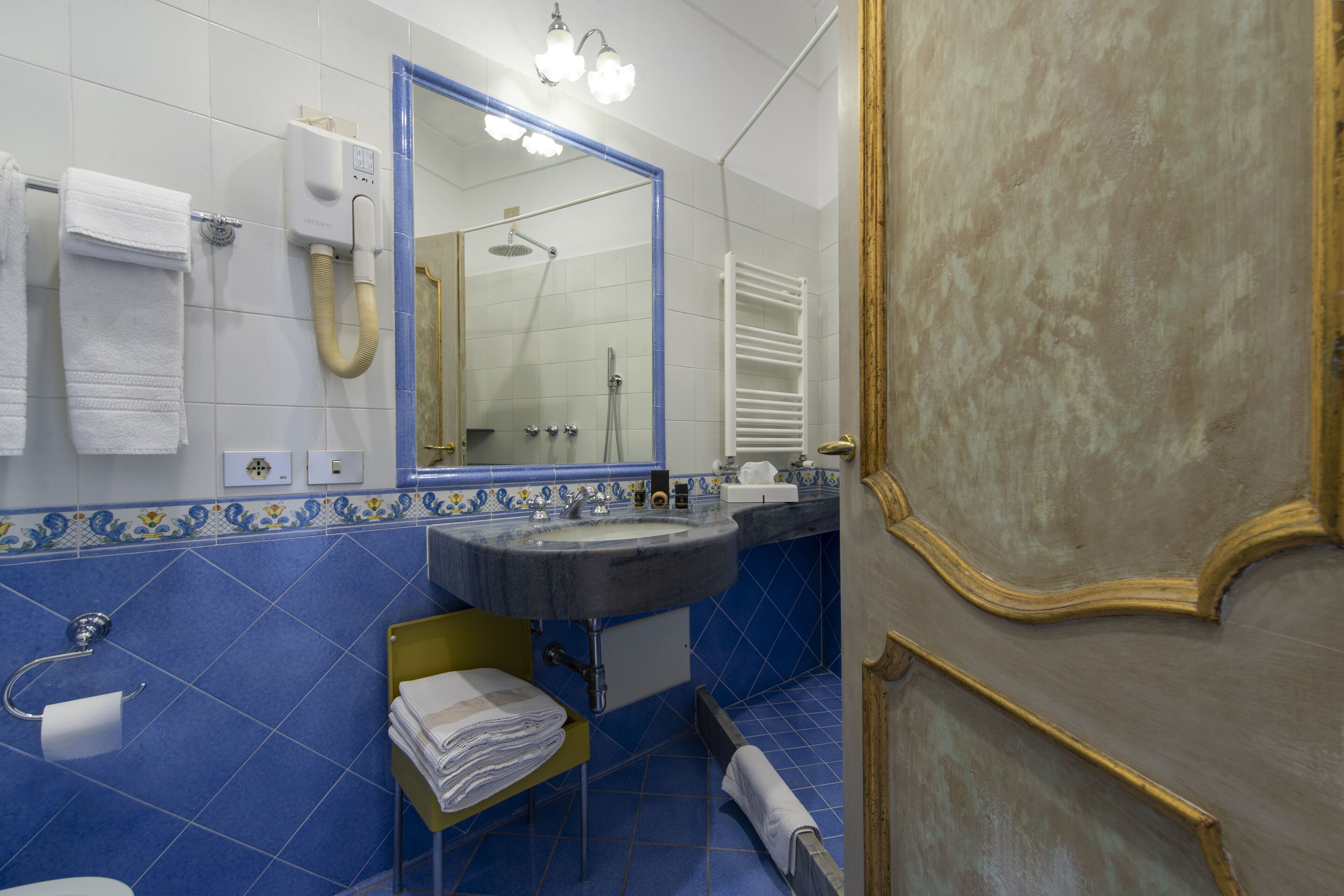 A bathroom with a sink, mirror, towel rack, and a shower.