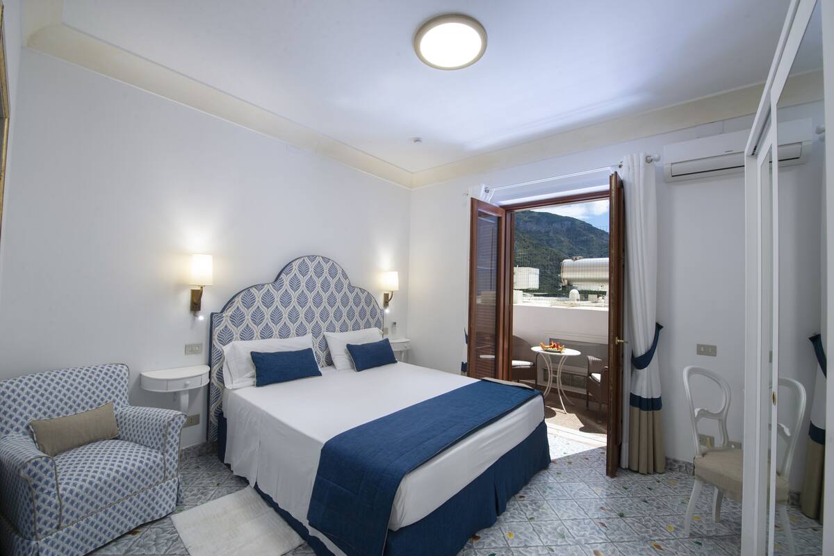 A bedroom with a bed, bedside tables, a chair, and a view of the outdoors.