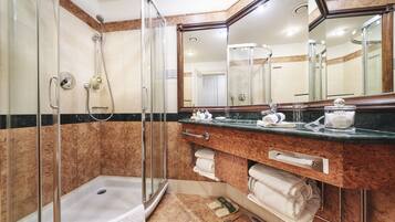 Un baño moderno con ducha de vidrio, tocador de mármol y un espejo grande.