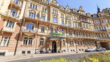A historic building with ornate architecture, a prominent entrance, and multiple flags.