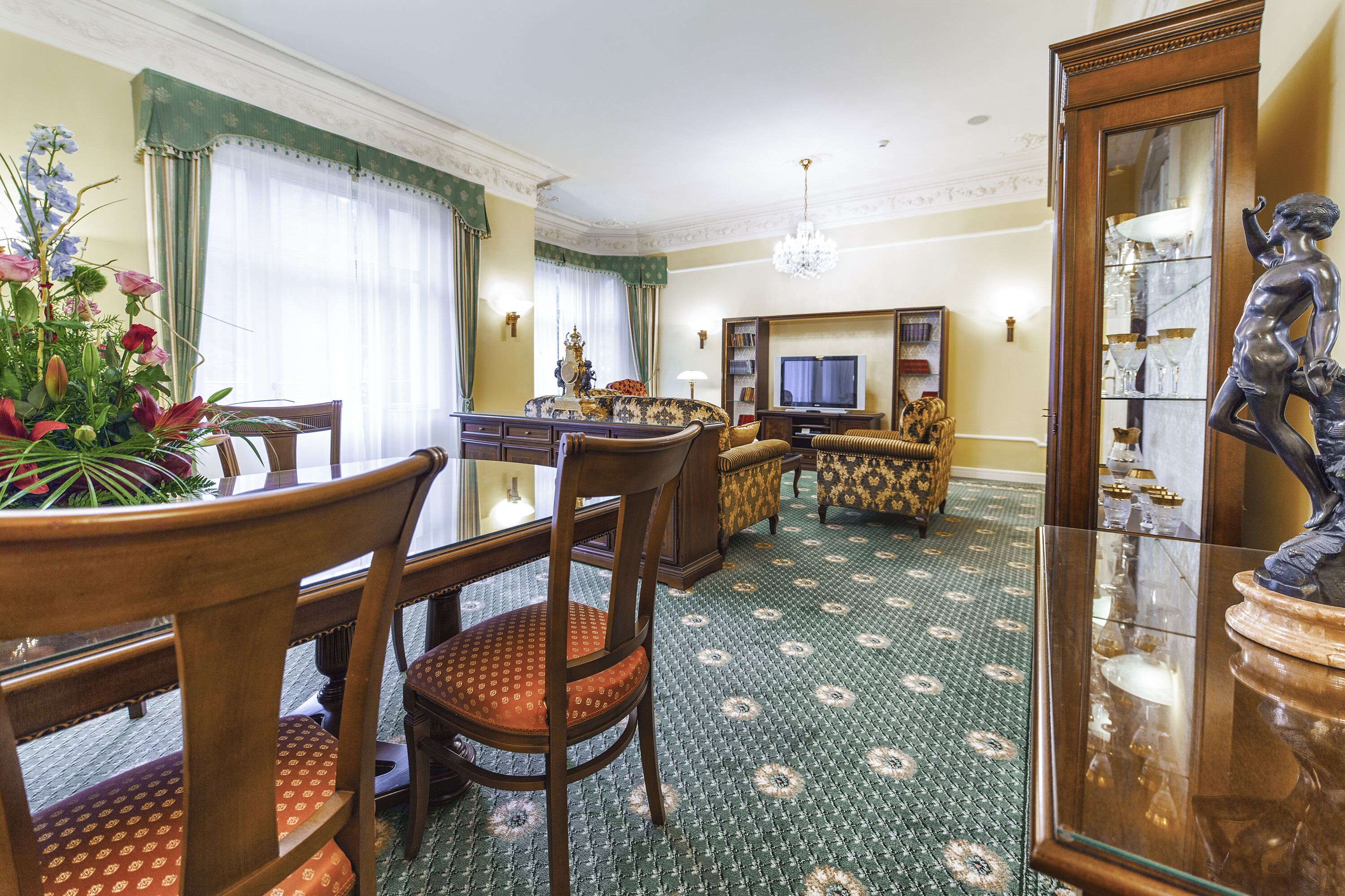 A dining area with a wooden table and chairs, a television, and a decorative statue.