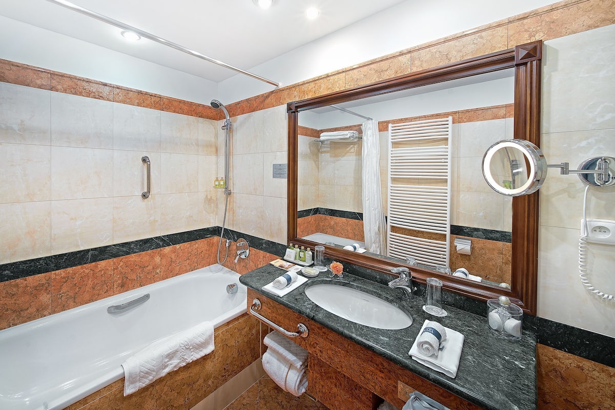 Une salle de bain avec une baignoire, deux lavabos, un grand miroir et une douche.