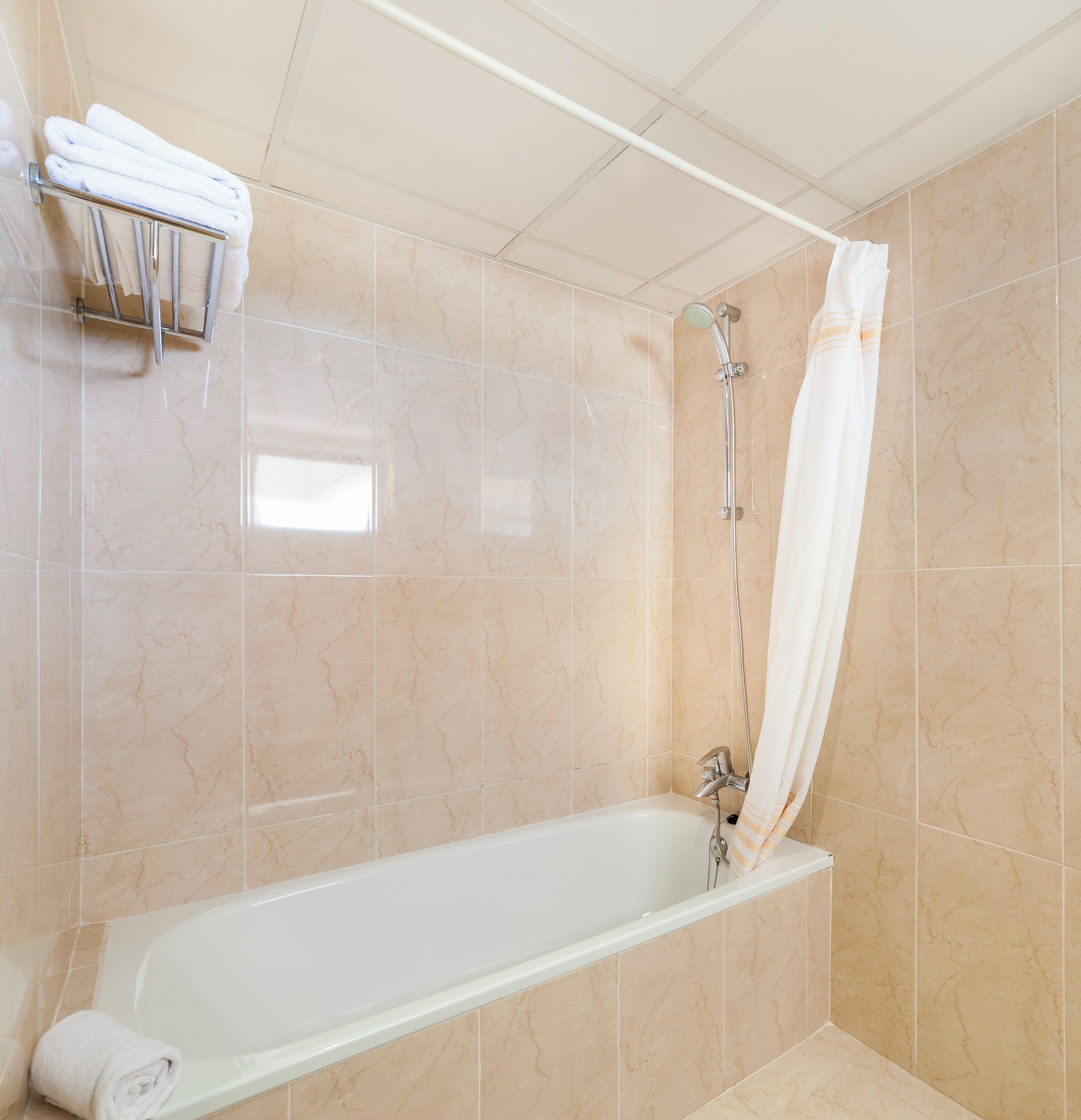 Un baño moderno con bañera, ducha con cortina y un perchero para toallas.