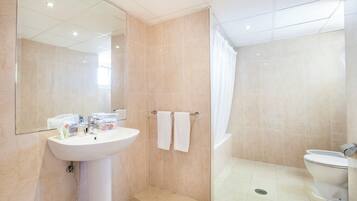 Un baño moderno con lavamanos, espejo y dos toallas en un perchero.