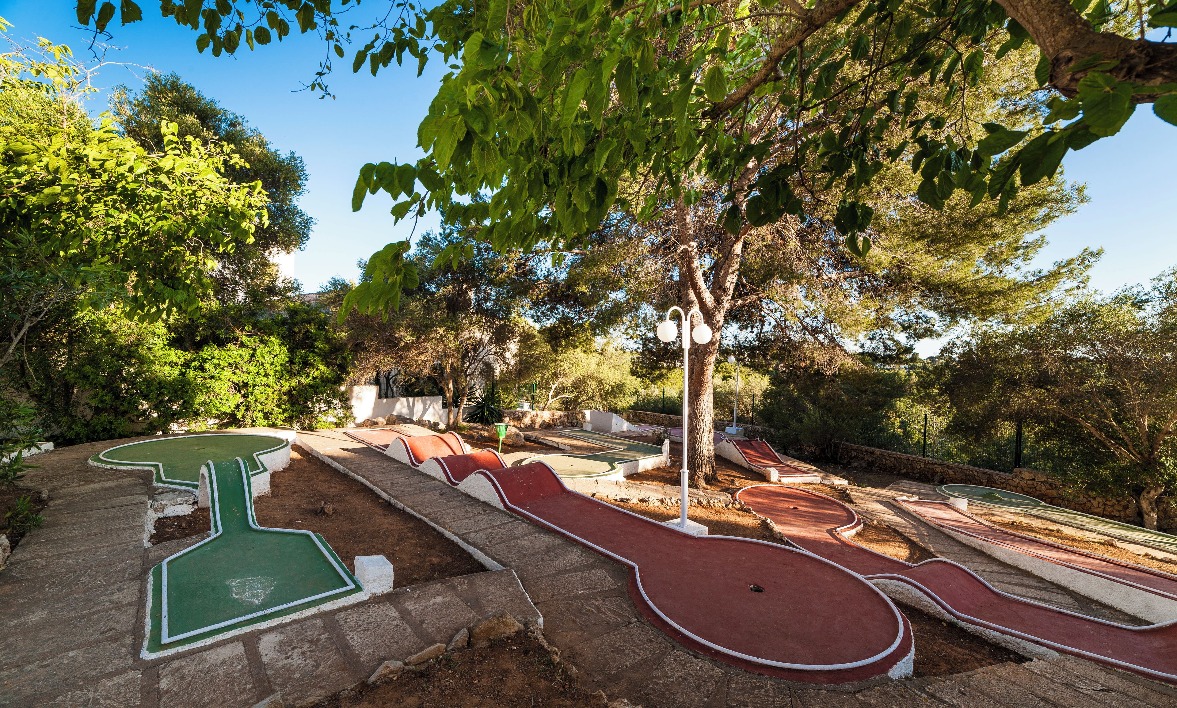 Un campo de mini golf con varios hoyos, rodeado de árboles y follaje.