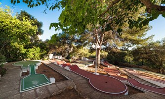 Un campo de mini golf con varios hoyos, rodeado de árboles y follaje.