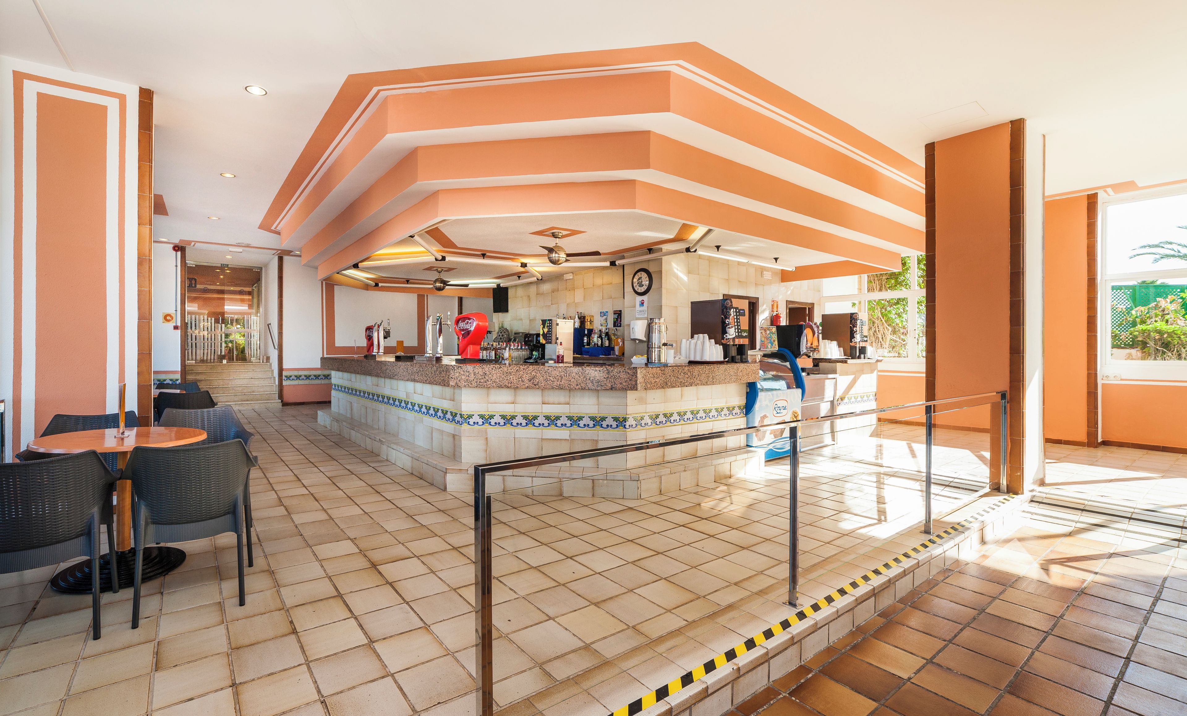 Una hall d'albergo con zona bar, posti a sedere e una scala che conduce a un piano superiore.
