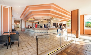 Un hall d’hôtel comprenant un bar, des espaces pour s’asseoir et un escalier menant à un étage supérieur.