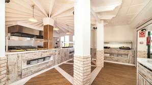 A modern kitchen with a central island, white brick columns, and a wooden floor. - Globales Samoa (Manacor)