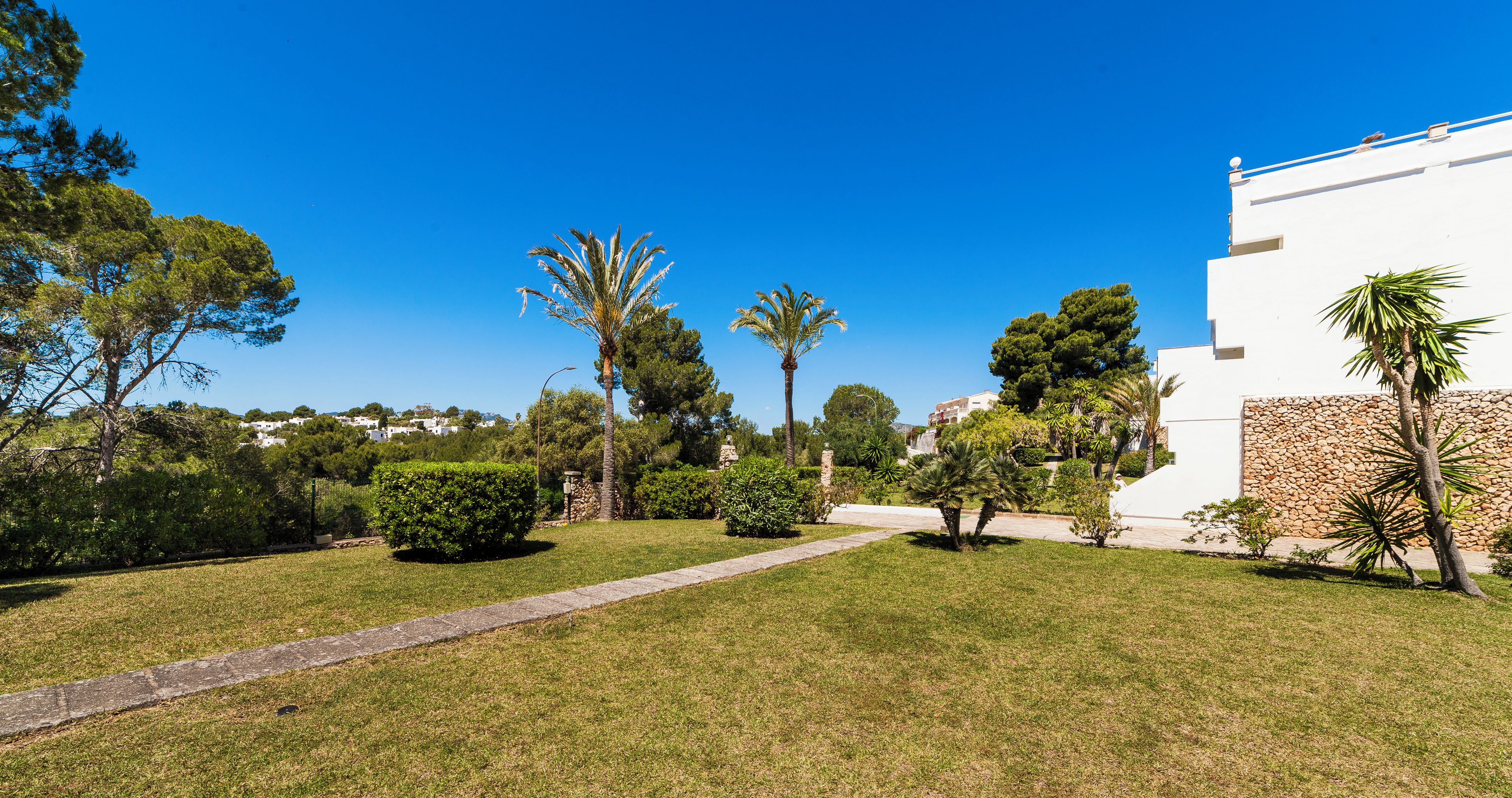 A well-maintained garden with a pathway leading to a white building with stone accents.