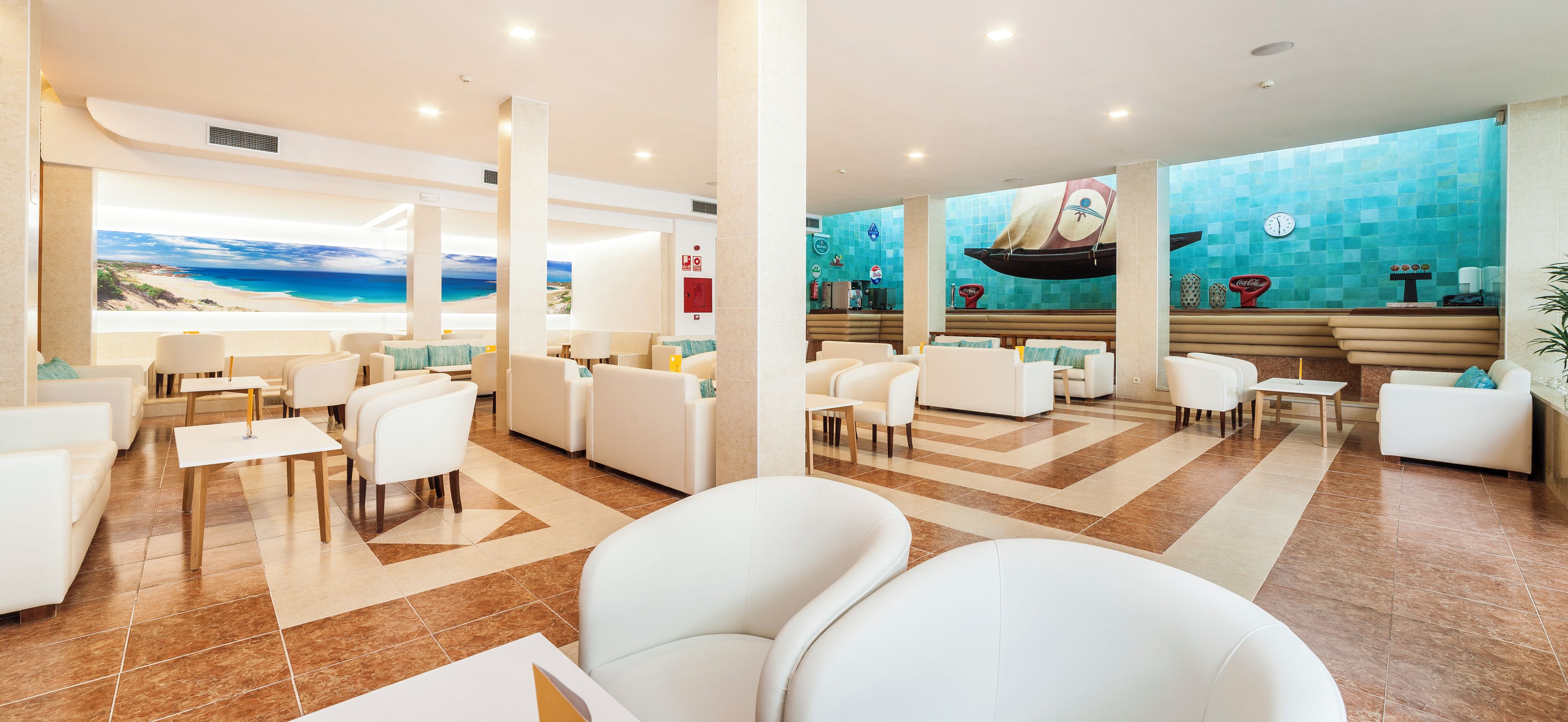 Vestíbulo de hotel con vista al mar, zonas de estar y una recepción.