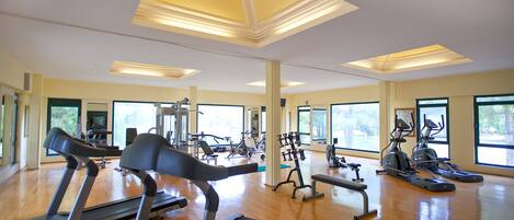 Un gimnasio amplio con cintas de correr, elípticas y equipo de pesas.