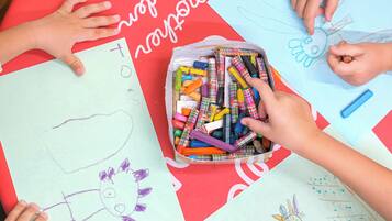 Una mesa con dibujos infantiles y una caja de ceras.
