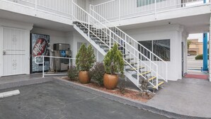 A multi-level building with a central staircase, a vending machine, and two large potted plants. - Motel 6 Norwalk, CA (Norwalk)