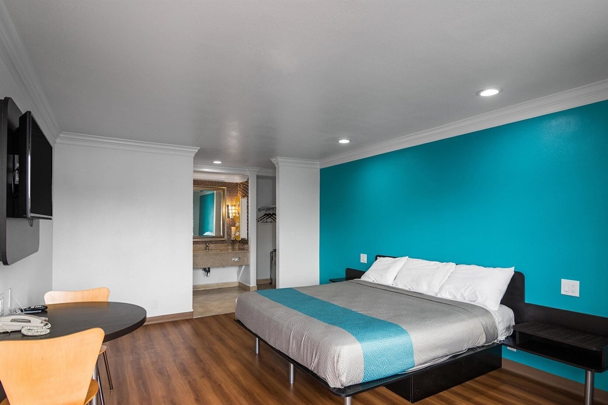 A modern hotel room with a bed, a desk, and a chair.